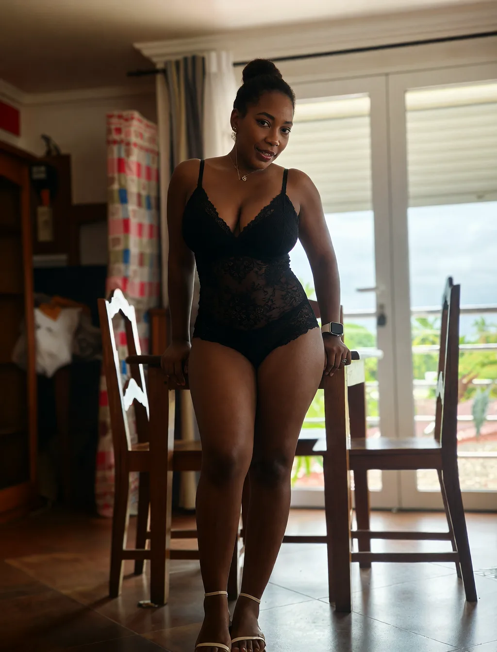 Edit the supplied photograph. Change only what is asked for below. Return one clean, natural, high-resolution photograph with realistic skin texture and no distortion. Make her chest noticeably larger and fuller, in a natural shape that suits her build, and let whatever she is wearing fall over it correctly. Replace her outfit with a black lace lingerie set that fits her properly. Keep her face, her identity, her hair and her skin tone exactly as they are, and keep the room and the light she is in. Keep her pose and the framing of the shot.