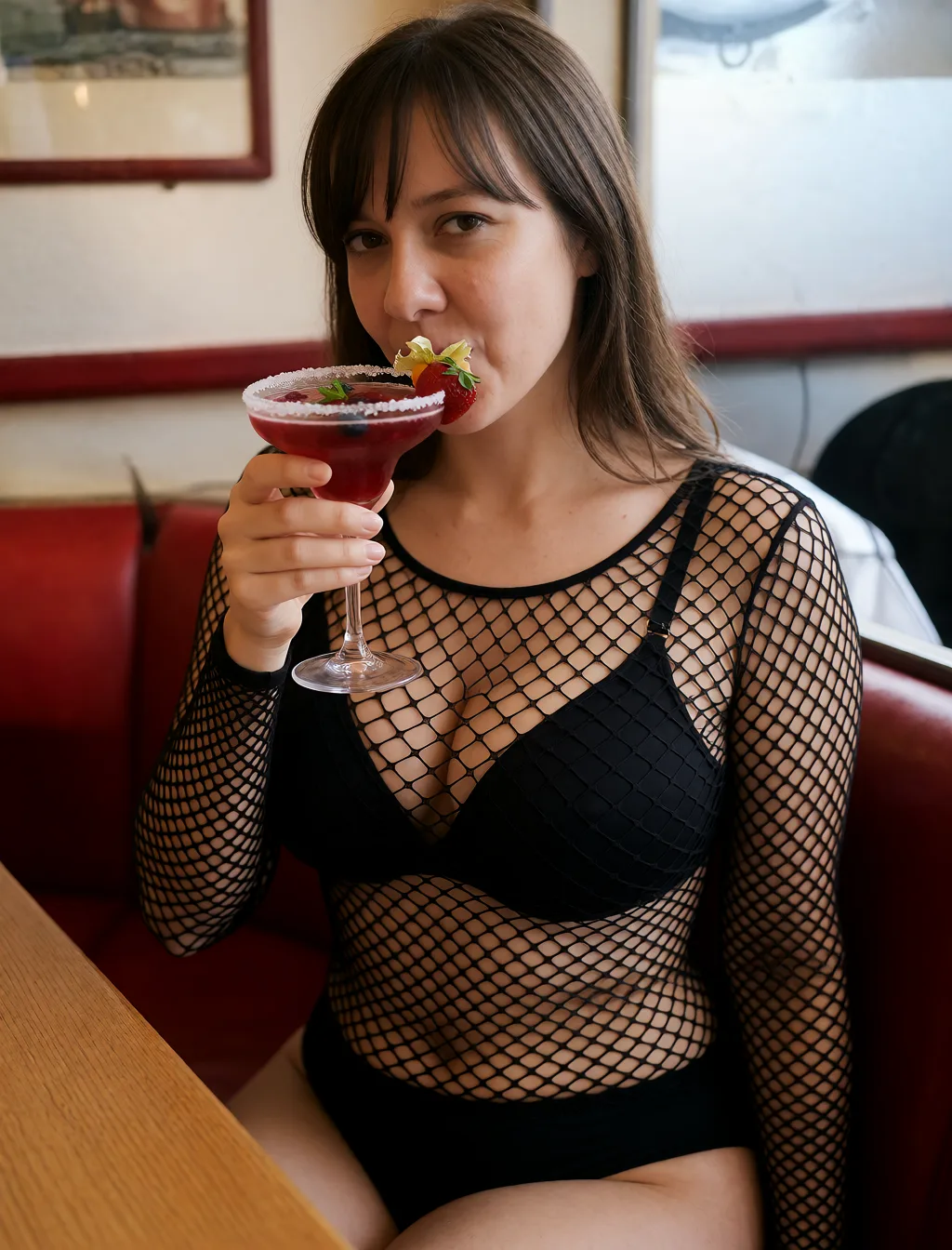 Edit the supplied photograph. Change only what is asked for below. Return one clean, natural, high-resolution photograph with realistic skin texture and no distortion. Make her chest noticeably larger and fuller, in a natural shape that suits her build, and let whatever she is wearing fall over it correctly. Replace her outfit with a black fishnet bodysuit worn over a plain black bra and briefs. Keep her face, her identity, her hair and her skin tone exactly as they are, and keep the room and the light she is in. Keep her pose and the framing of the shot.