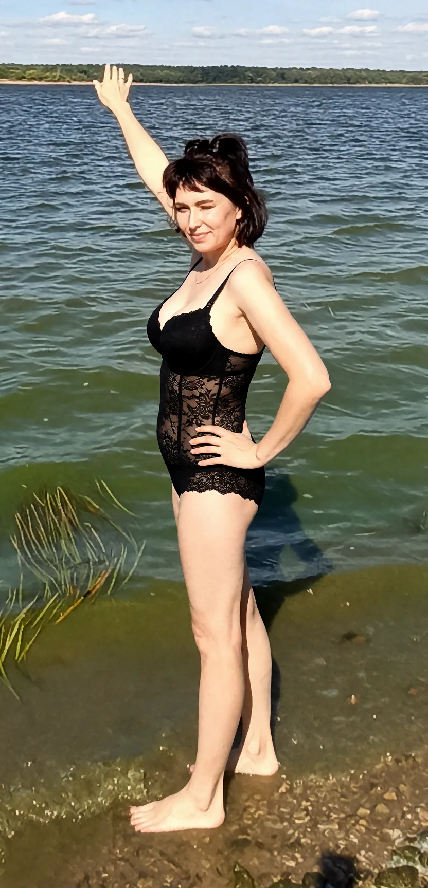 Edit the supplied photograph. Change only what is asked for below. Return one clean, natural, high-resolution photograph with realistic skin texture and no distortion. Replace her outfit with a black lace lingerie set that fits her properly. Keep her face, her identity, her hair and her skin tone exactly as they are, and keep the room and the light she is in. Keep her pose and the framing of the shot.