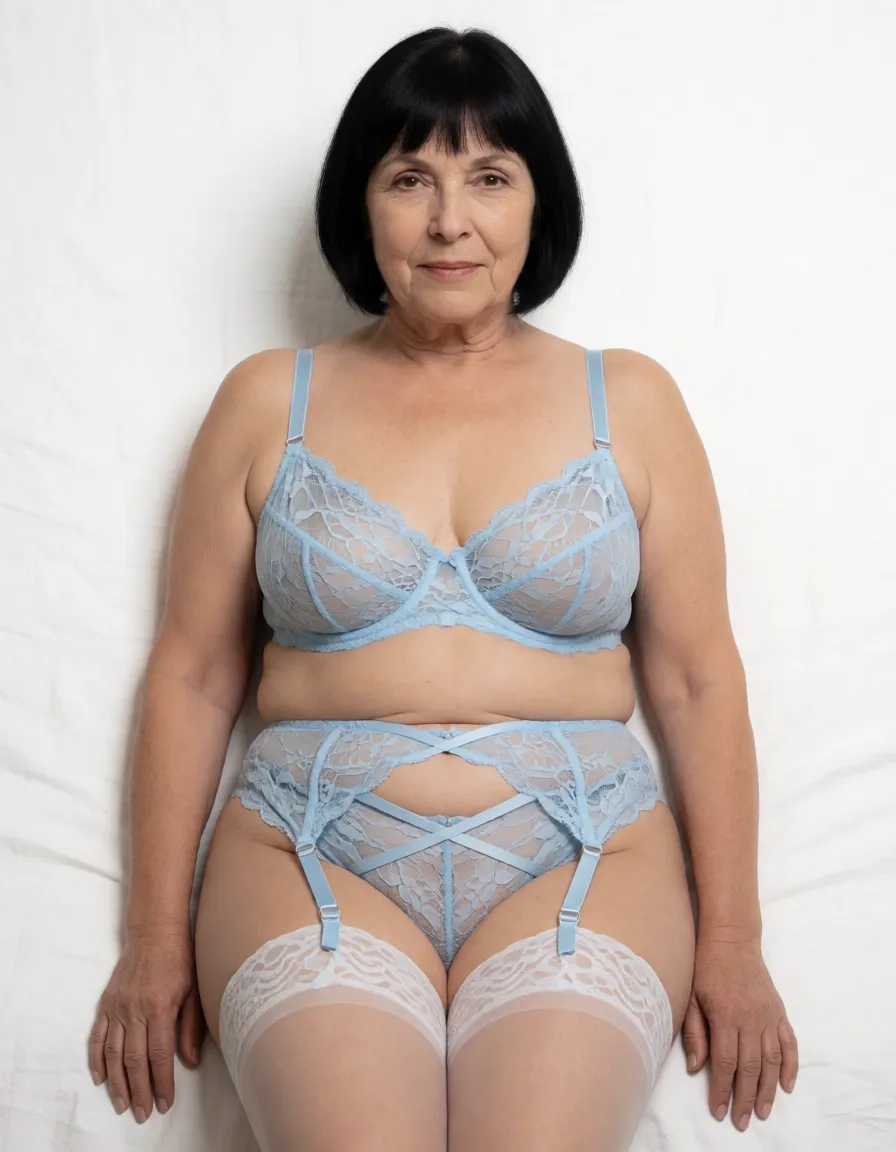 a studio photograph, A full-body portrait of a wrinkled flabby chubby 66 year old woman with very pale skin, short straight dark black hair featuring straight bangs, a sexy facial expression with closed mouth and direct gaze toward the viewer, brown eyes, finely narrow very wrinkled face and narrow wrinkled neck, laying on her back on a bed centered in the frame with her shoulders relaxed and flabby wrinkled arms hanging naturally at her sides with hands relaxed, wearing a loose fitting light blue lace bra with thin straps, a matching light blue lace garter belt with crisscross straps attached to sheer white stockings with lace tops that highlights her chubby flabby thighs and fat knees, her upper thighs have cellulite, the bra and garter belt sheer and semi-transparent revealing the wrinkled cleavage of her deflated very saggy natural medium sized breasts with stretch marks and fine wrinkles, a very sagging fat flabby chubby bottom heavy muffin top belly with stretch marks and love handles, narrow hips with dips, her body facing forward in a neutral pose with legs raised, bent at the knees and spread wide open, the bottom of her flat sagging buttocks and dark brown pubic hair can be seen, her entire head, torso legs and feet can be seen., even shadowless studio light, plain white background, clean rich colour, flawless polished skin, strikingly beautiful, radiant complexion, early twenties
